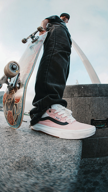 A fisheye shot of Kyle Walker holding a skateboard and wearing the Kyle Walker Wafflecup skate shoes.
