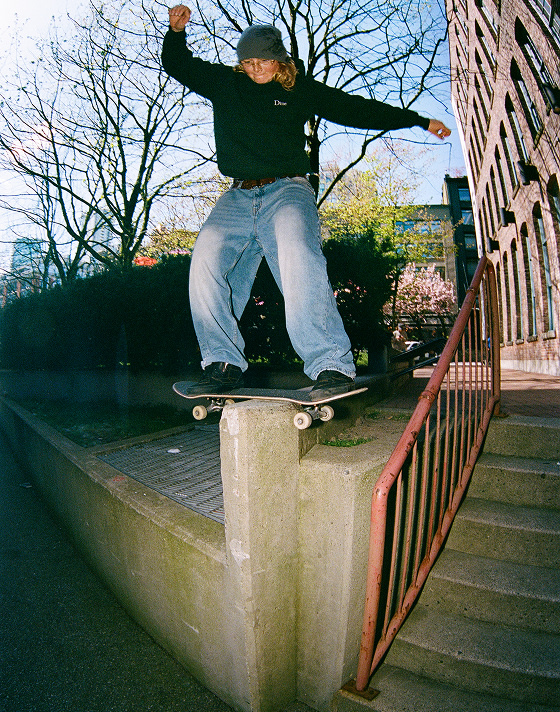 Vans Skate Team Rider Una Farrar boardslides a concrete rail in a city center wearing Skate Half Cab.