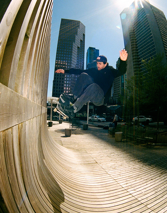Vans Skate Team Rider Rick McCrank ollies off a wall in a city center wearing black Skate Old Skool shoes.