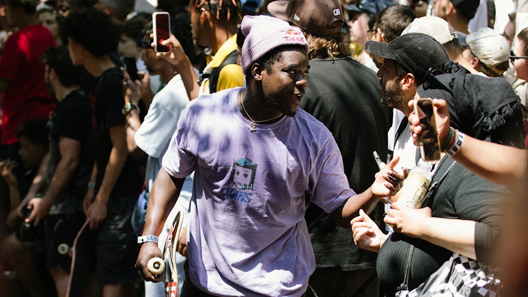 Pro skateboarder Zion Wright smiling towards a packed crowd of people holding their phones at him.