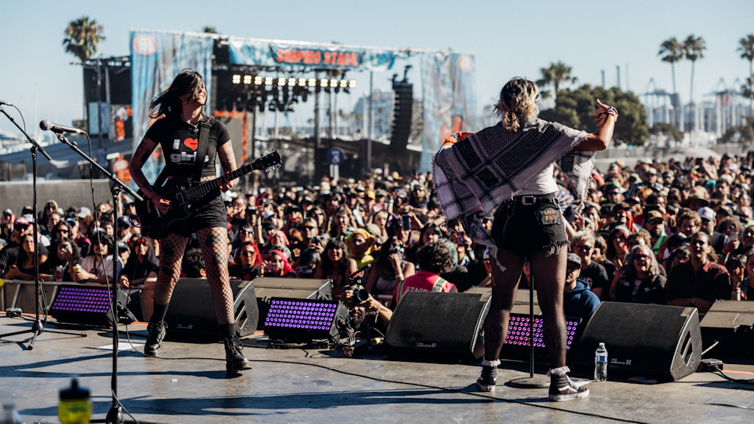 A band at Warped Tour playing during the daytime in front of a crowd.