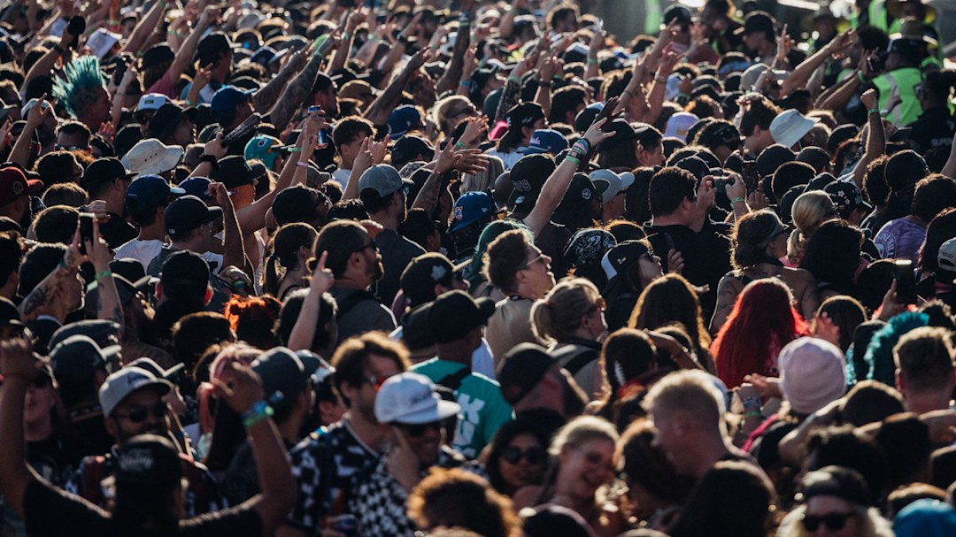 The crowd at Warped Tour Long Beach throwing horn signs with their hands.