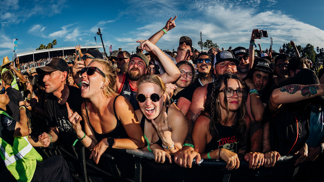 The crowd leaning over the rail near a concert stage at Warped Tour Long Beach 2025.