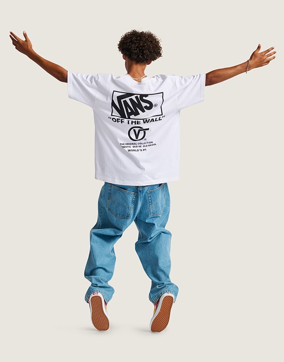 A kid jumps in a photography studio wearing a white Vans “Off the Wall” tee and blue jeans.