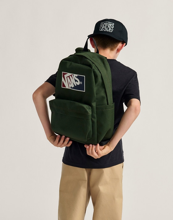 Close-up of a kid adjusting the dried kelp green Kids Old Skool Grom Backpack in a photography studio.