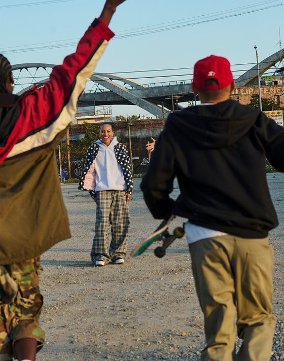 A group of friends hang out in a gravel parking lot wearing Vans shoes and clothes to create an urban scene.