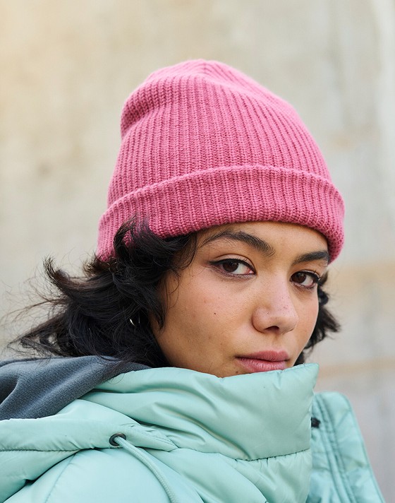 A young woman looks into the camera wearing a light blue MTE Hillgate Puffer and a mauvewood Core Basic Cuff Beanie.