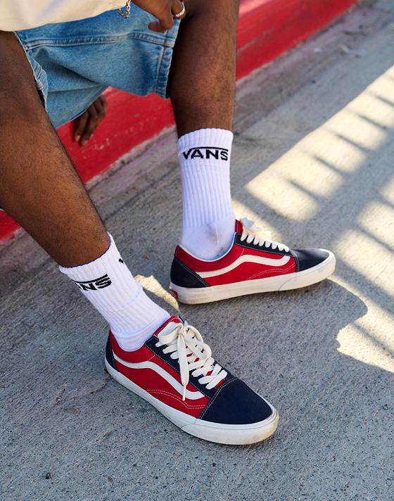 A close-up of the red and navy Old Skool with white crew socks on the street.