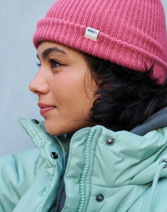 The side profile of a young woman dances wearing a light blue MTE Hillgate Puffer with a Core Basic Cuff Beanie.