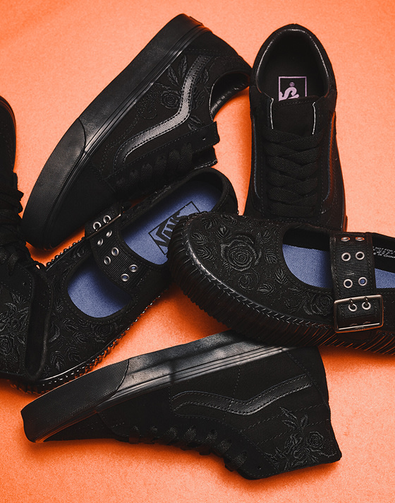 A black Mary Jane Creeper, Old Skool, and Sk8-Hi with black embroidered flowers lie on an orange floor from the Blackout Pack.