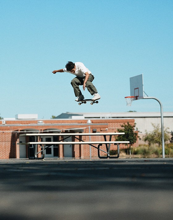Vans Skate Team Rider Nick Michel jumping over a playground table wearing white Skate Half Cab from the United Through Skateboarding collection.