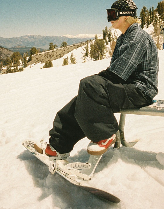 Vans Snowboard Team Rider Mia Brookes sits on a bench on a snowy slope wearing the Encore Pro.