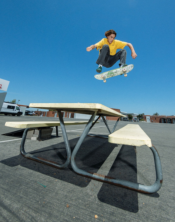 Vans Skate Team Rider Curren Caples jumps over a table on a playground wearing the Curren from the United Through Skateboarding collection.