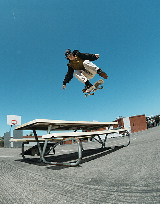 Vans Skate Team Rider Shiloh Catori jumps over a table wearing black Skate Old Skool 36+ from the United Through Skateboarding collection.