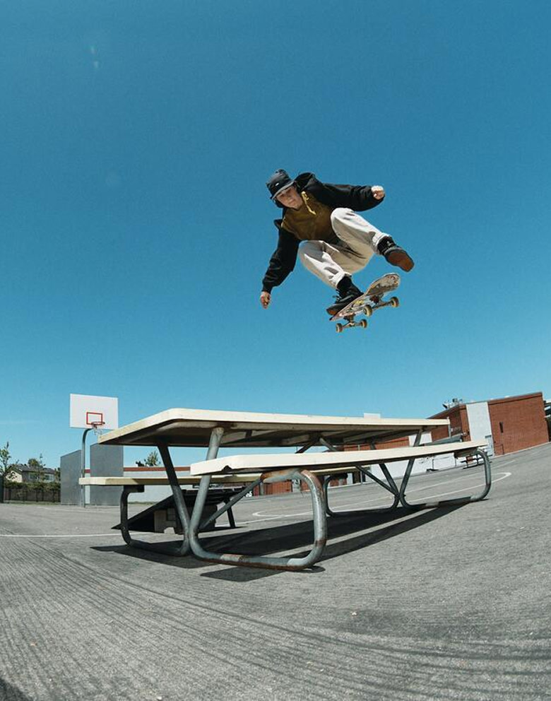 Atiba Jefferson photographs Vans Skate Team Rider Shiloh Catori jumping a table on a playground for the United Through Skateboarding collection.
