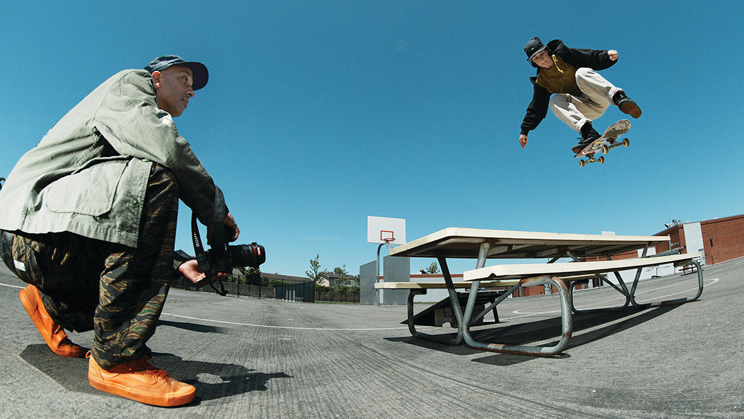 Atiba Jefferson photographing and skater doing a trick over a table.