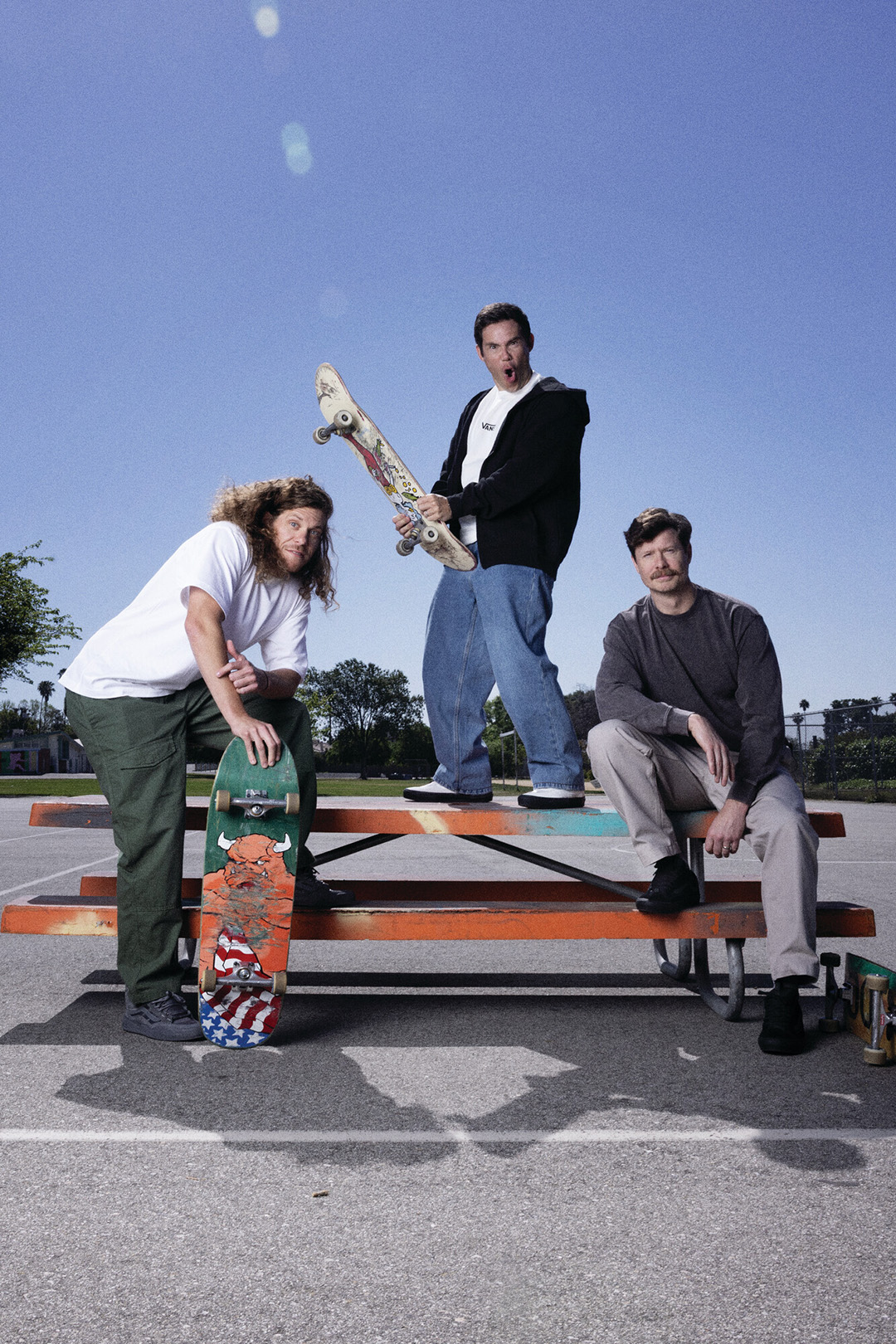 Cast of Workaholics posing with skateboarding on a table.