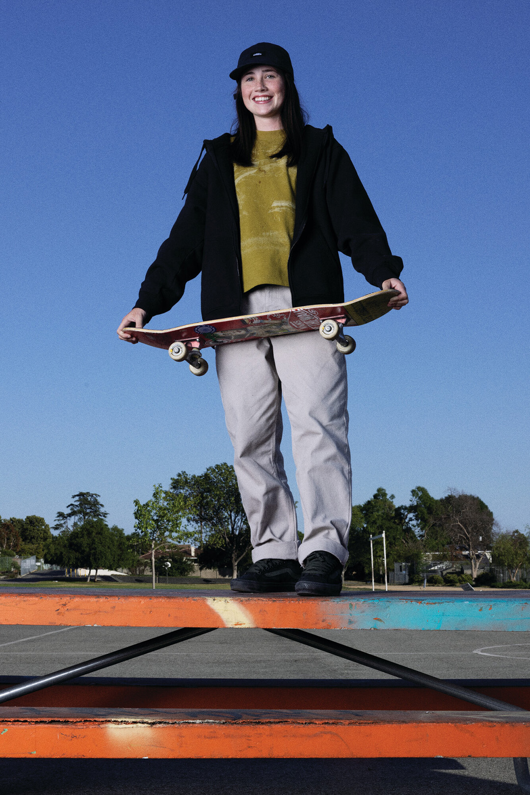 Shiloh Catori standing on a table holding a skateboard.