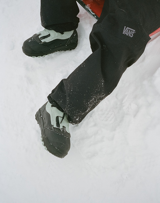 A knee-down shot of someone wearing the Infuse snowboard boot with black snowboard pants.