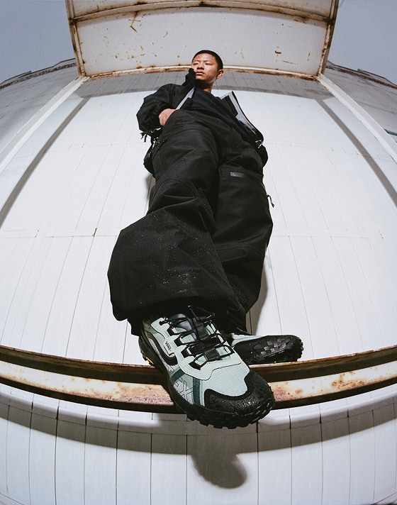 A close-up of water spraying onto and deflecting off of the exterior of the blue Crosspath XC GORE-TEX.