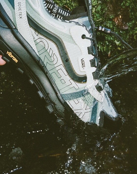 A close-up of water spraying onto and deflecting off of the exterior of the blue Crosspath XC GORE-TEX.