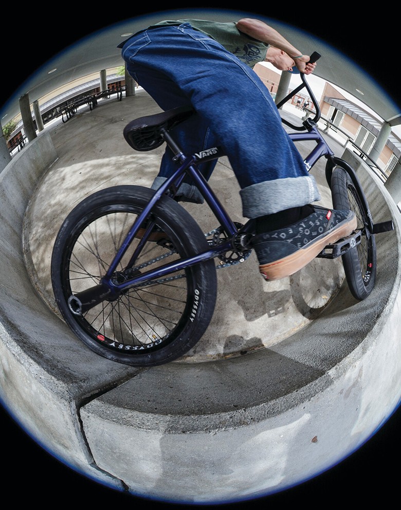A fisheye shot of someone riding a BMX bike on a wall wearing the black BMX Proof WaffleCup.