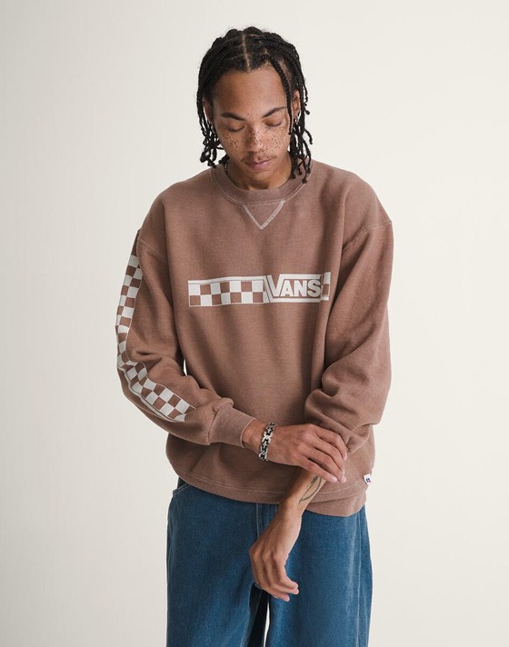A young man wears blue Check-5 Baggy Denim Pants with white Old Skool and a white t-shirt in a photography studio.