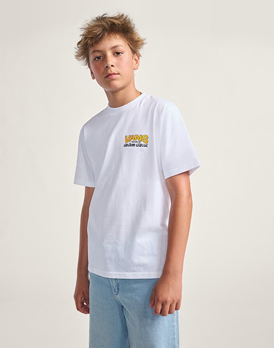 A kid jumps in a photography studio wearing a white Vans “Off the Wall” tee and blue jeans.