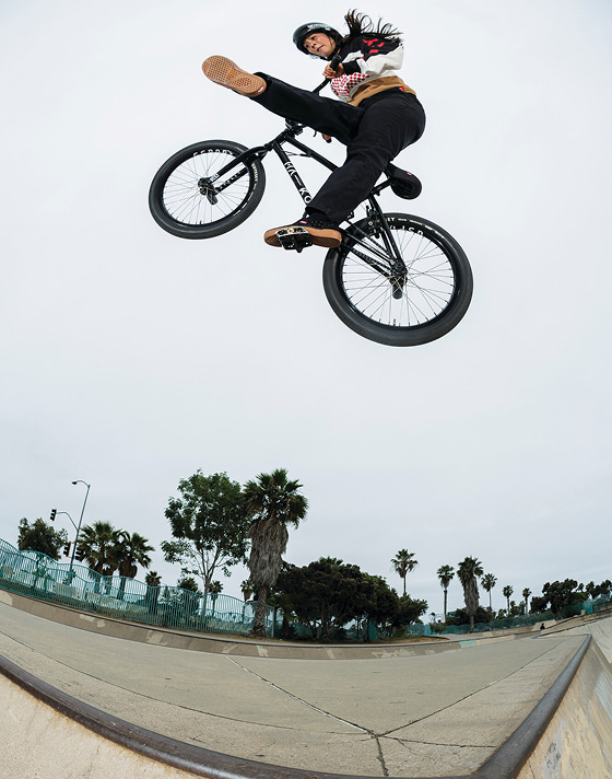 Vans BMX Team Rider Perris Benegas rides her bike and jumps down into a floodway on a sunny day wearing the Vans x Odyssey BMX Proof WaffleCup.
