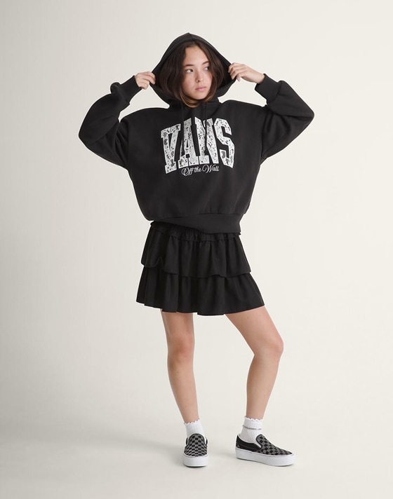 A young woman poses in a photography studio wearing a black Ava Tiered Mini Skirt.