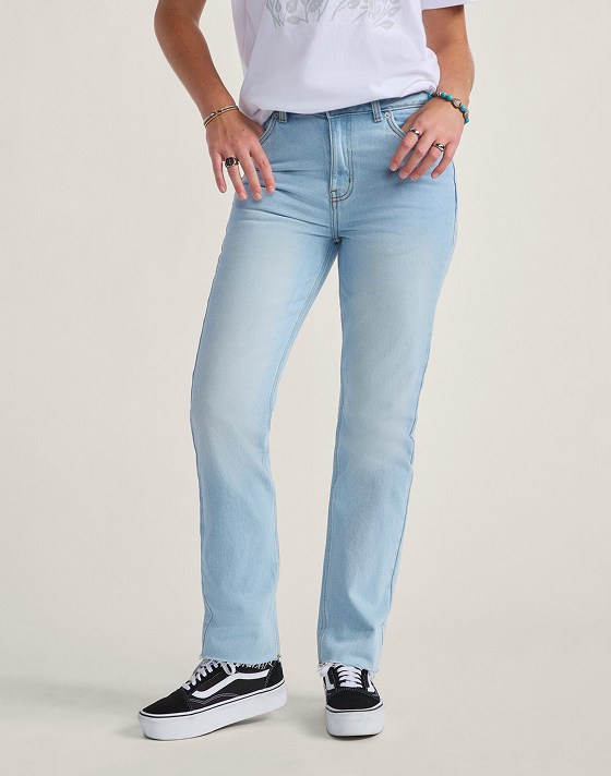 A waist-down shot of a woman wearing blue Annabelle Pants with black and white Old Skool in a photography studio.