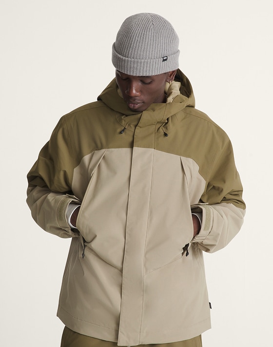 A young man checks the fit of his Vans raincoat in a photography studio.