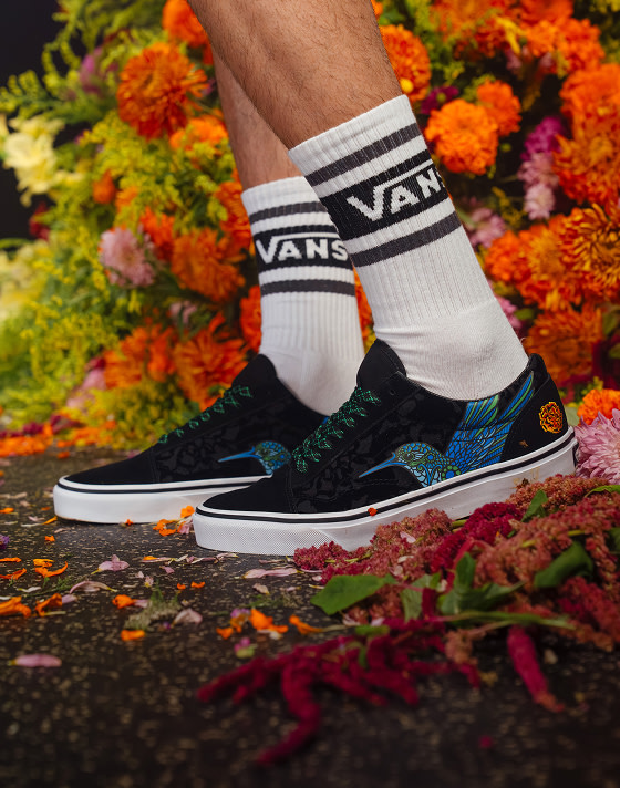 A close-up of the hummingbird and marigold patterns on the Old Skool for Día de Muertos in a photography set with flowers everywhere.