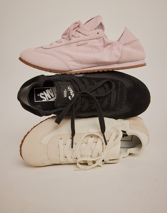 A pink, black, and white Super Lowpro Collapse are stacked on top of each other in a photography studio.