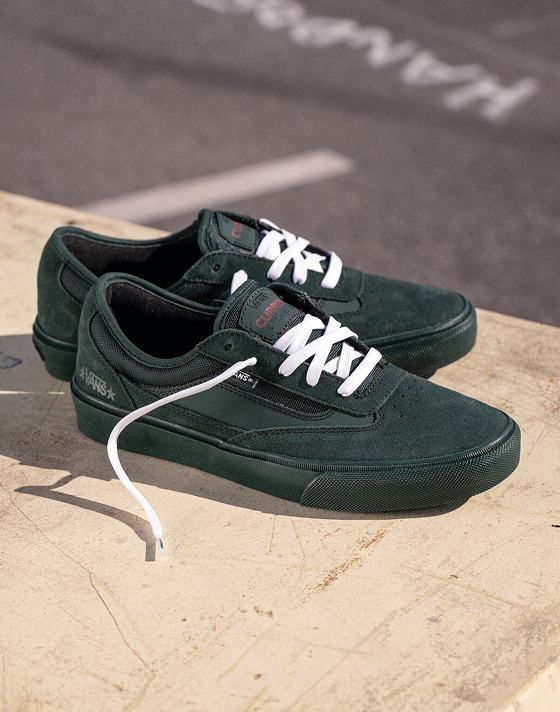 A pair of dark green Skate Curren shoes lie on a table on a playground from the United Through Skateboarding collection.