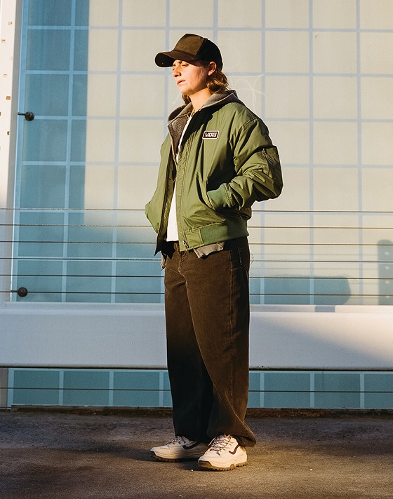 A woman wearing the red and white Sk8-Hi GORE-TEX with a green Vans jacket in the city.