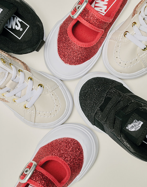 An overhead shot of glittery kids’ shoe styles in a photography studio.