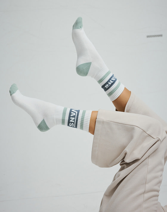 Close-up on white Vans crew socks in the air as someone lays on their back in a photography studio.