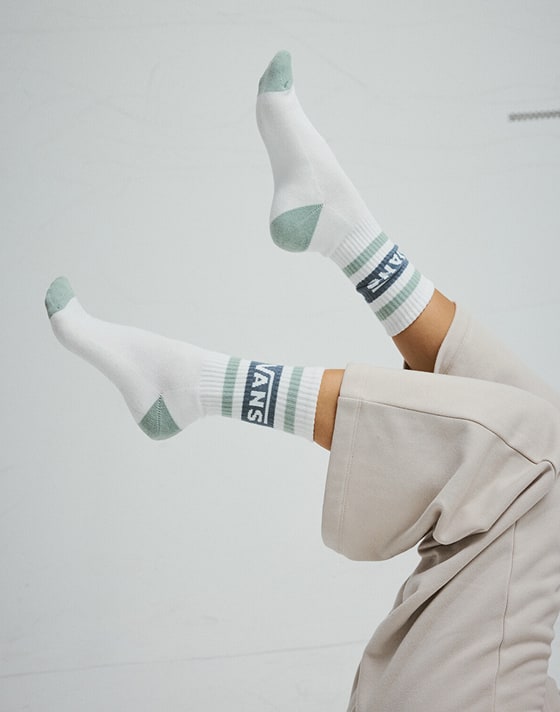 A close-up of a young woman wearing a silver chain and a Vans Off the Wall logo sweater in a photography studio.