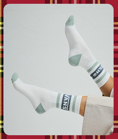 Gros plan sur des chaussettes montantes Vans blanches en l’air alors qu’une personne est allongée sur le dos dans un studio photo.