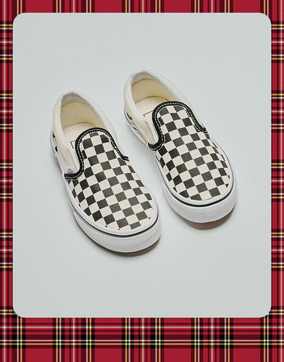 A photograph surrounded by a plaid holiday border of a pair of black and white Checkerboard Classic Slip-On in a photography studio.