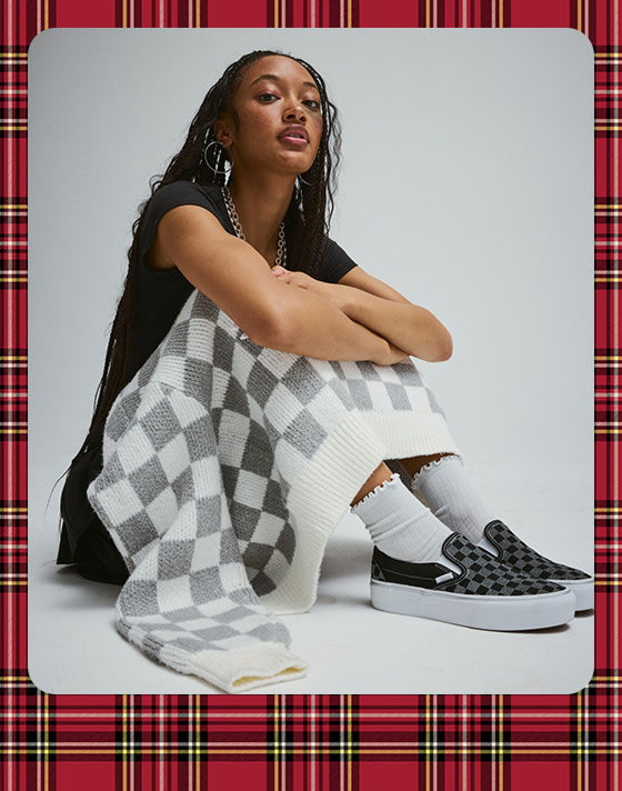 A photograph surrounded by a plaid holiday border of a young woman wearing the Evelyn Cardigan Sweater.