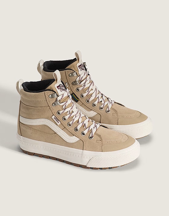 Une paire de Sk8-Hi Insulated beige et blanche dans un studio photo.