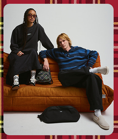 A young man and woman sit on an orange sofa in Vans shoes and clothes in a photography studio.