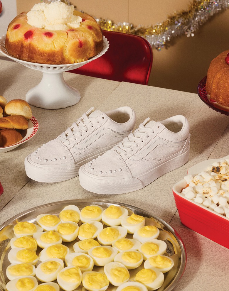 Gros plan sur les Old Skool blanc nacré posés sur une table de dîner garnie de plats des Fêtes, dont un gâteau aux fruits, des œufs mimosa et plus encore.