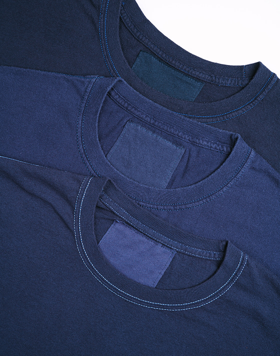Three vintage blanks of blue tees lay on top of each other with different hues to each blue.