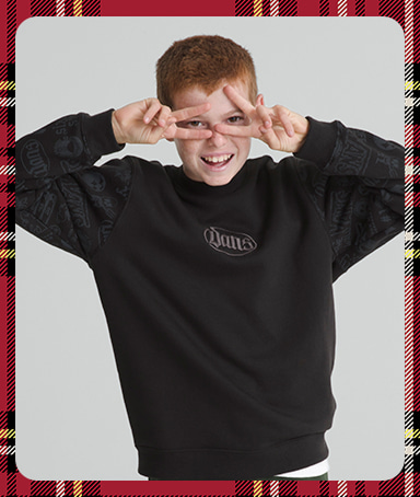 A photograph surrounded by a plaid holiday border of a young boy posing in a photography studio in a black Vans hoodie.