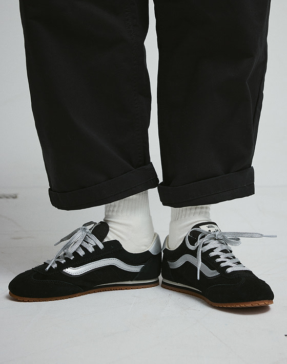 Close-up on the black and silver Super Lowpro with white crew socks and black pants.