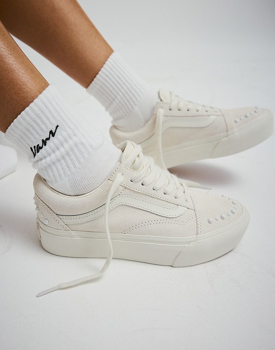 Close-up of the white Old Skool Pearlized paired with white Vans script logo crew socks in a photography studio.