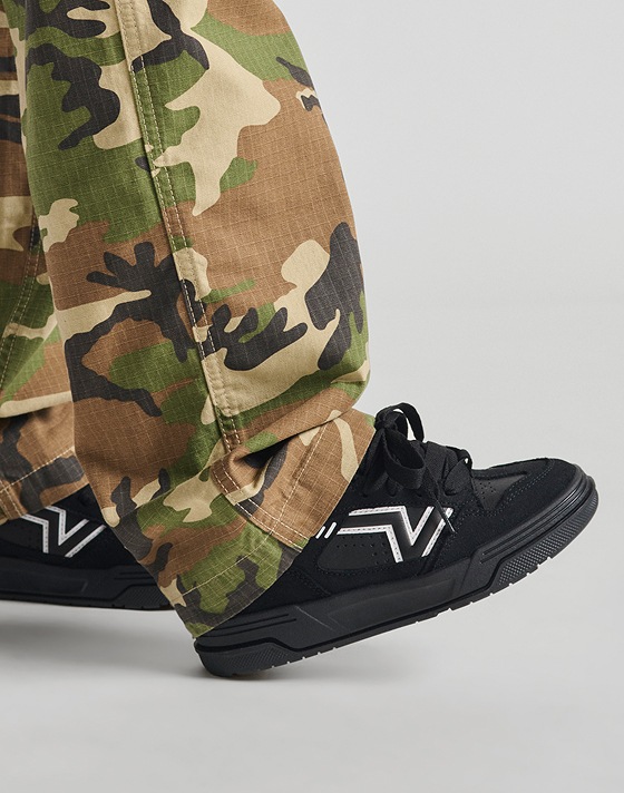 Close-up of black and white Upland shoes paired with camo pants.